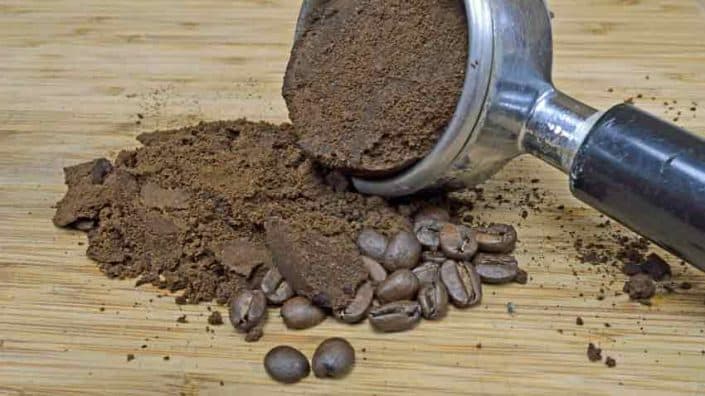 A coffee grinder and some beans on the ground