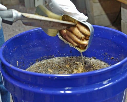 A person is using tongs to stir something in a bowl.