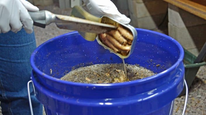 A person is using tongs to stir something in a bowl.