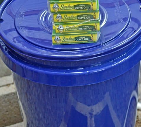 A blue trash can with some green plastic bags in it