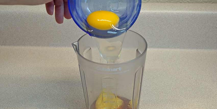 A person is pouring lemon juice into a glass.