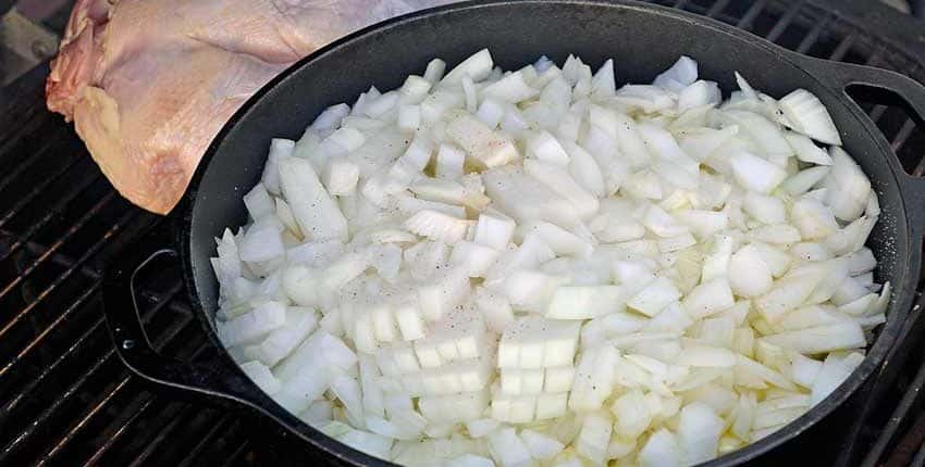 A pan of onions is cooking on the stove.