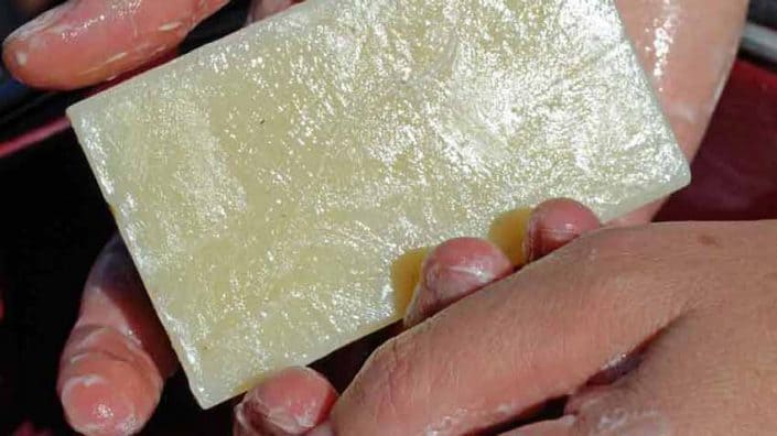 A person holding a piece of cheese in their hand.