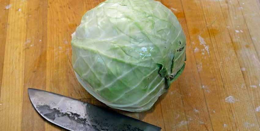 A cabbage sitting on top of a wooden table.