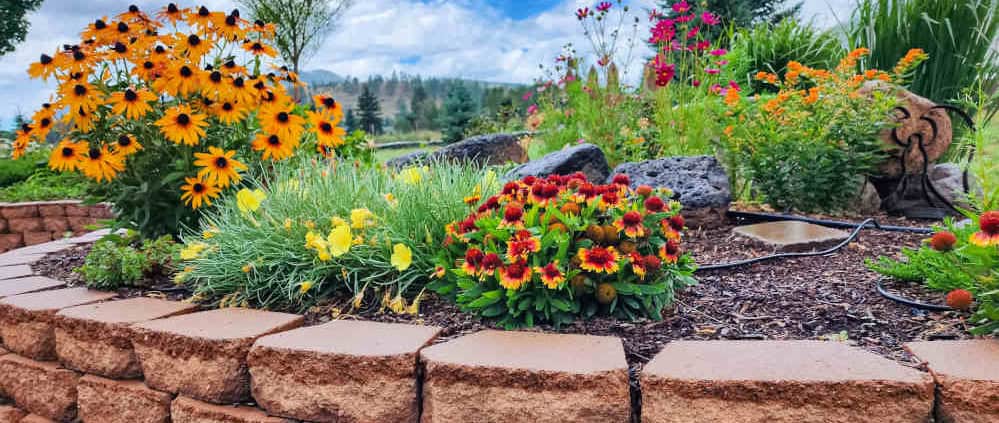 A raised block planter with native and pollinator attracting flowers in it.